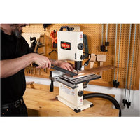 Image of a man using a push stick to safely push a workpiece past the bandsaw blade.