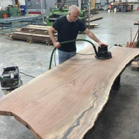 Image of a man using the sander on a large wood slab